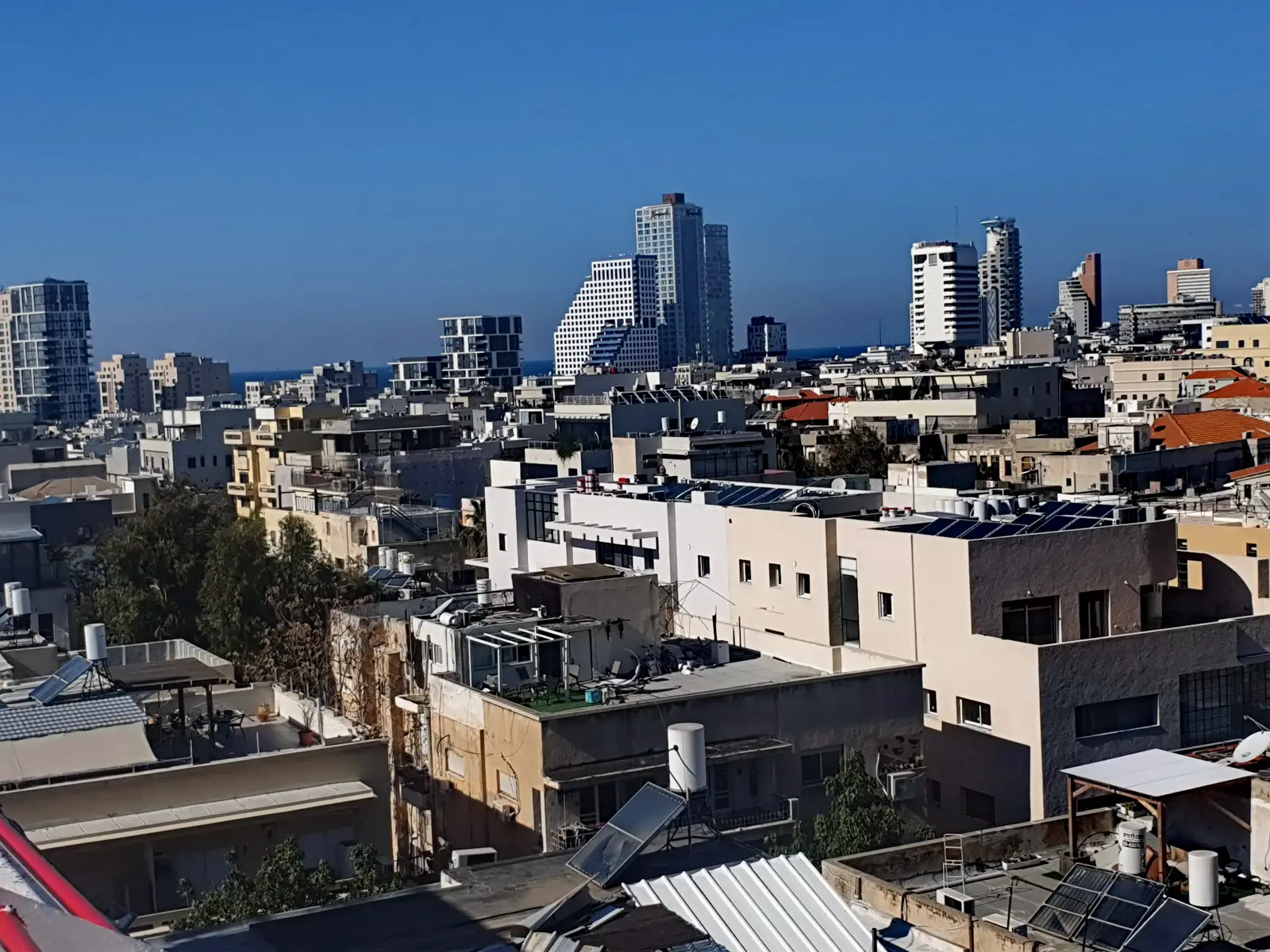 מבט על גגות בנייני מגורים בתל אביב, עם דודי שמש ופאנלים סולאריים
